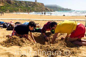 A csoportvezető a gyerekekkel gödröt ás a strandon