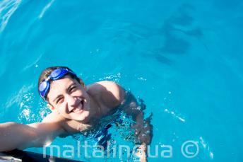 Egy diák úszik a hajóhoz közel Cominón.
