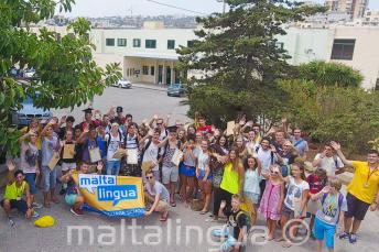 A junior tanulók egy nagy csoportja integet a nyári iskola előtt