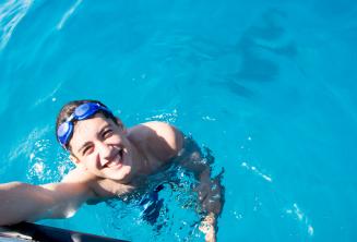Egy diák úszik a hajóhoz közel Cominón.